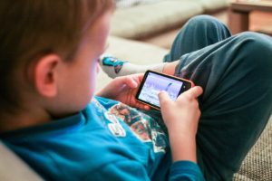 Little boy playing video games on his phone - discussing the scary stuff with your child